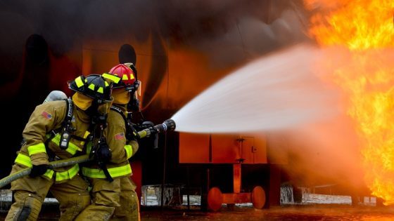 zwei Feuerwehrmitarbeiter löschen einen Brand